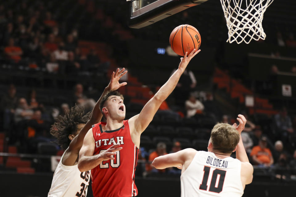 Utah guard Lazar Stefanovic (20) drives to the basket between Oregon State's Glenn Taylor Jr., left, and Tyler Bilodeau during the second half of an NCAA college basketball game in Corvallis, Ore., Thursday, Jan. 26, 2023. Utah won 63-44. (AP Photo/Amanda Loman)