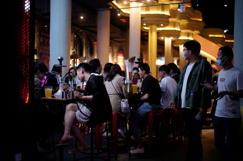 People wearing face masks are seen at a bar area in a nightclub after it reopens in Shanghai