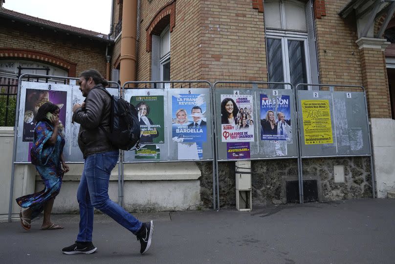 People walk past a row of campaign posters for the upcoming European election in Courbevoie, west of Paris, Thursday, June 6, 2024.