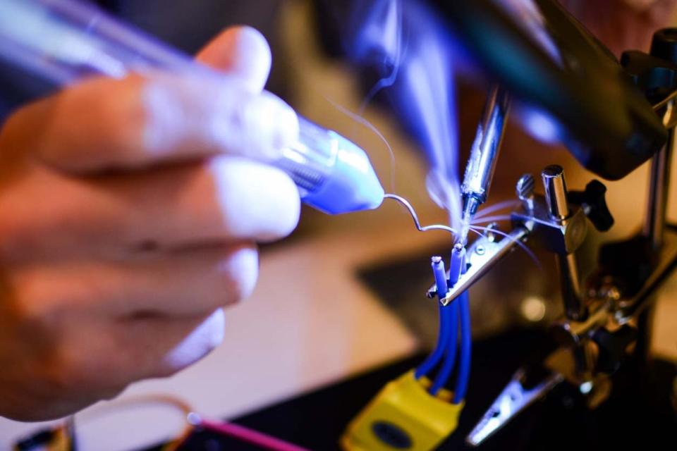 A close up of a person using tools on blue wires. 