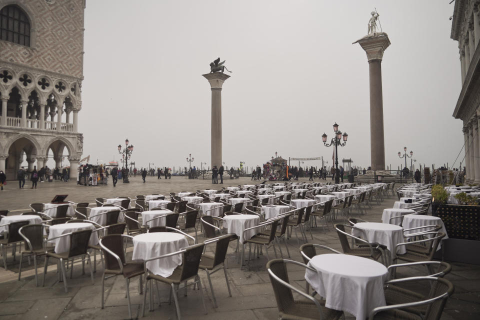 FILE - In this Feb. 25, 2020 file photo, empty tables sit in St. Mark's square in Venice, Italy. Still reeling from the effects of major flooding just a few months ago, Venice faces a new emergency: the threat of a new virus outbreak across Italy that is scaring international visitors world-wide and hitting the economy hard. (AP Photo/Renata Brito)