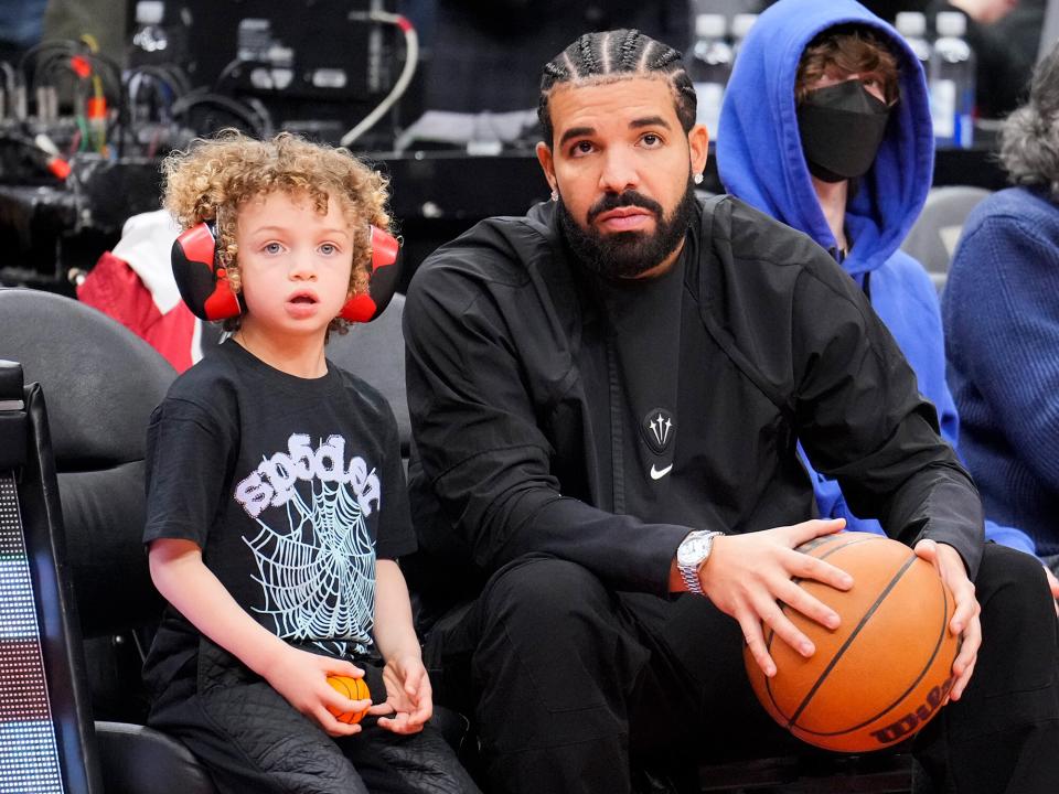 Drake sits with his son Adonis before the Toronto Raptors play the Philadelphia 76ers in their basketball game at the Scotiabank Arena on April 7, 2022 in Toronto, Ontario, Canada