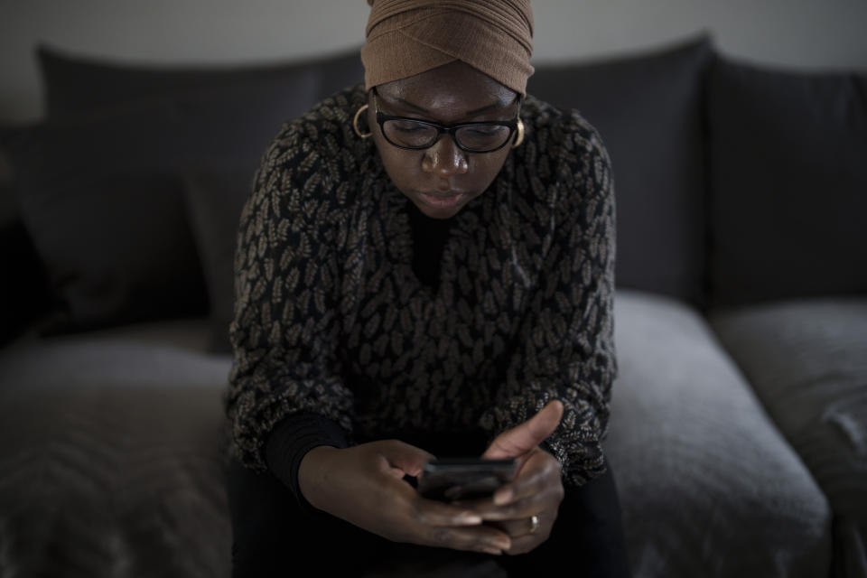 May Sow, cuyo sobrino Alassane Sow desapareció tras embarcar en un cayuco en Mauritania con la intención de llegar a Europa, mira su celular en su casa en Orleans, Francia, el 22 de noviembre de 2022. (AP Foto/Felipe Dana)