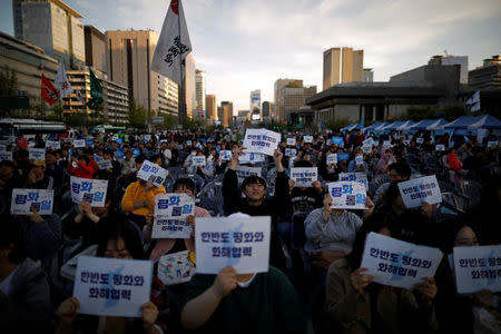 People hold placards that read "Peace, reconciliation and cooperation on the Korean peninsula" during a rally to wish for a successful inter-Korean summit, in central Seoul, South Korea, April 21, 2018. REUTERS/Kim Hong-Ji