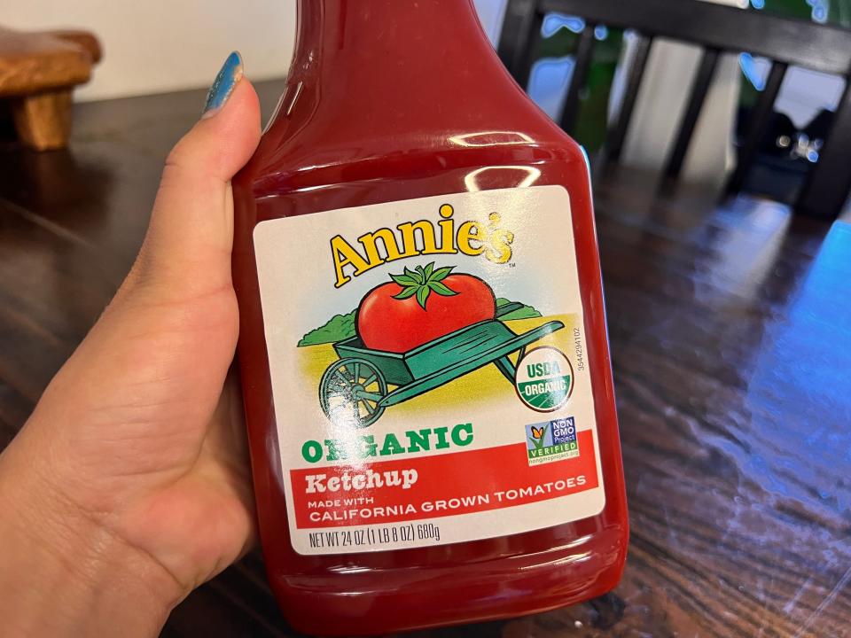 Hand holding bottle of Annie's organic ketchup