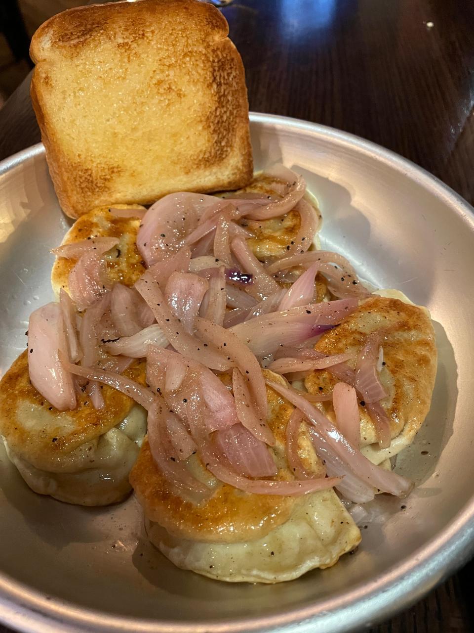 Cast Iron offers several variations of pierogi. Here is the potato, Gouda and bacon, topped with onions and served with garlic bread.