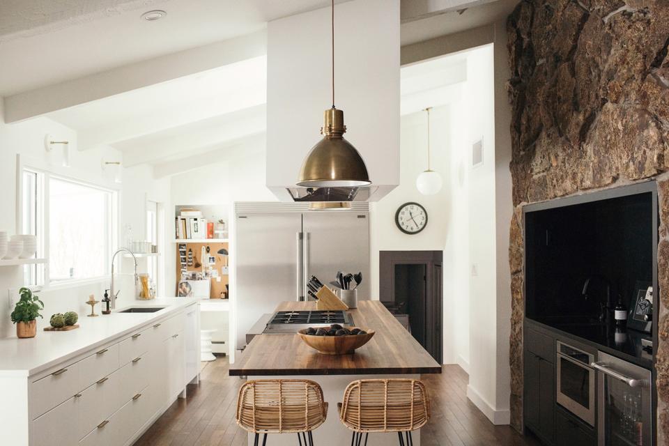 AFTER: Using 3D modeling, Laura and Scott were able to determine that the hood looked best at the center of the room, surrounded by a walnut island and quartz countertops. Pairs of Crate and Barrel pendants and Asher + Rye counter stools complete the look.