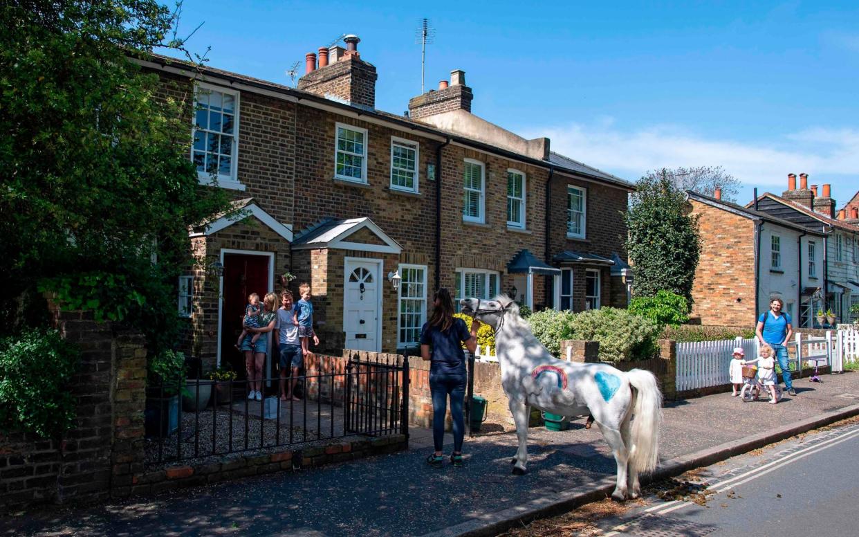 Family members Bryony (2L) Alice (L), who's 2nd birthday it is today, Stanley (R) and Paul Blant (2R), stand on their doorstep looking at a Welsh mountain pony Annie's Wizz held by handler Daisy Cinque outside their home in Twickenham, south west London on April 23, 2020.  - Justin Tallis/AFP via Getty