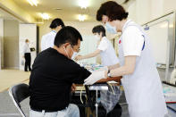 A nurse takes a blood sample from a resident in Natori, Miyagi prefecture, northern Japan, Monday, June 1, 2020. The Japanese Health Ministry began testing around 10,000 people for coronavirus antibodies on Monday to better understand its spread. (Kyodo News via AP)
