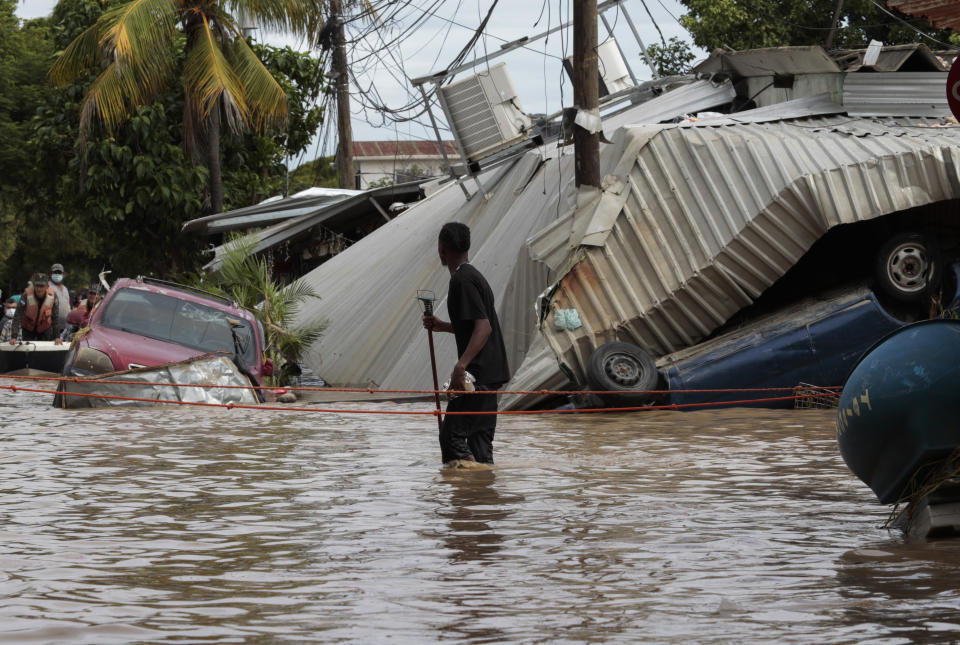 FILE - In this Nov. 6, 2020, file photo, a resident walking through a flooded street looks back at storm damage caused by Hurricane Eta in Planeta, Honduras. As Eta moved back over Caribbean waters, governments in Central America worked to tally the displaced and dead, and recover bodies from landslides and flooding that claimed dozens of lives from Guatemala to Panama. This year has seen record Atlantic hurricanes and western wildfires, devastating floods in Asia and Africa and a hot, melting Arctic. It's not just been a disastrous year, but a year of disasters. (AP Photo/Delmer Martinez, File)