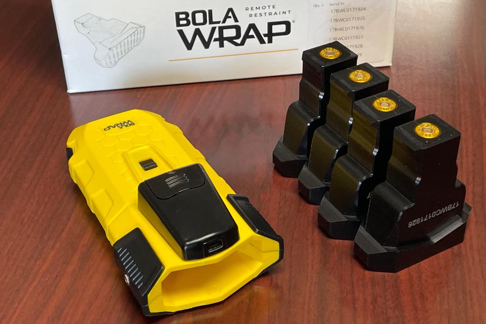 The BolaWrap restraining system uses a blank pistol cartridge to fire a small Kevlar cord, which is designed to wrap around the arms or legs of a person. The system consists of one-time use cartridges, which are fired from a laser-guided hand-held device.