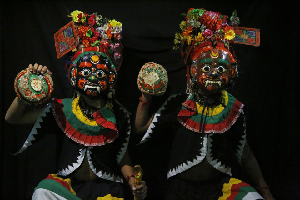 In this Sept. 23, 2018, photo, dancers pose for photographs wearing mask of god Bhot Bhairabh in Kathmandu, Nepal. For centuries, Nepal has celebrated the Indra Jatra festival of masked dancers, which officially begins the month-long festivities in the Hindu-dominated Himalyan nation. The dancers, who come from a variety of backgrounds, pull off this performance every year despite minimal financial support from the government and other sources, they say. (AP Photo/Niranjan Shrestha)