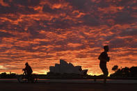 A jogger runs past the Sydney Opera House at dawn in Sydney, Wednesday, July 28, 2021. Australia’s largest city Sydney will remain in lockdown for another four weeks due to a growing COVID-19 cluster. (Mick Tsikas/AAP Image via AP)