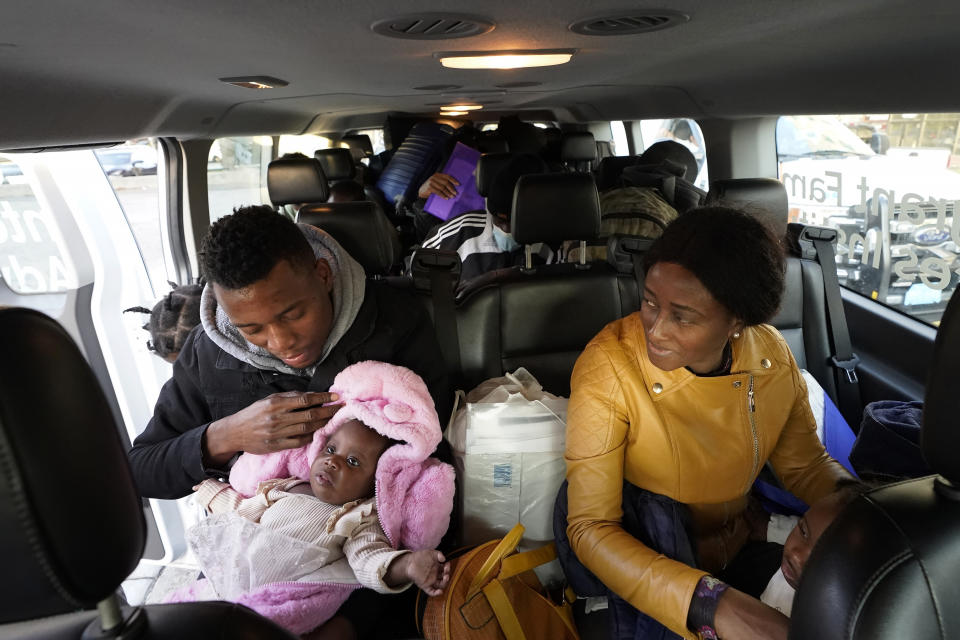 Petterly Jean-Baptiste, left, holds a child as he and his wife Leonne Ysnardin, right, both immigrants from Haiti, load into a van in Boston, along with other immigrant families while waiting for transportation to a shelter in Quincy, Mass., Thursday, Nov. 16, 2023. Across the region, advocates relied on a patchwork of temporary shelters including churches, hospital waiting rooms and even airport lounges after Massachusetts' emergency shelter system hit a state-imposed limit of 7,500 families last week. (AP Photo/Steven Senne)