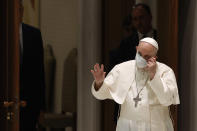 Pope Francis takes off his protective mask as he arrives to attend his weekly general audience in the Paul VI hall at the Vatican, Wednesday, Aug. 4, 2021. It was Francis' first general audience since undergoing planned surgery to remove half his colon for a severe narrowing of his large intestine on July 4, his first major surgery since he became pope in 2013. (AP Photo/Riccardo De Luca)
