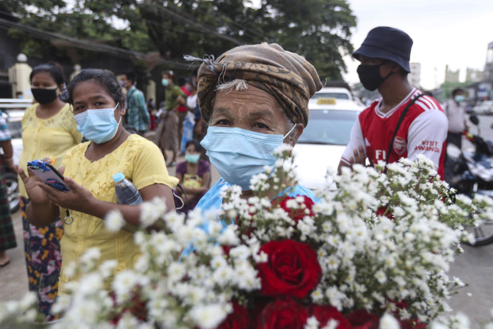 A woman holds flowers to welcome prisoners as she waits outside Insein prison in Yangon, Myanmar, Friday, April 17, 2020. Myanmar says it is releasing almost 25,000 prisoners under a presidential amnesty marking this week's traditional Lunar New Year celebration.(AP Photo/Thein Zaw)