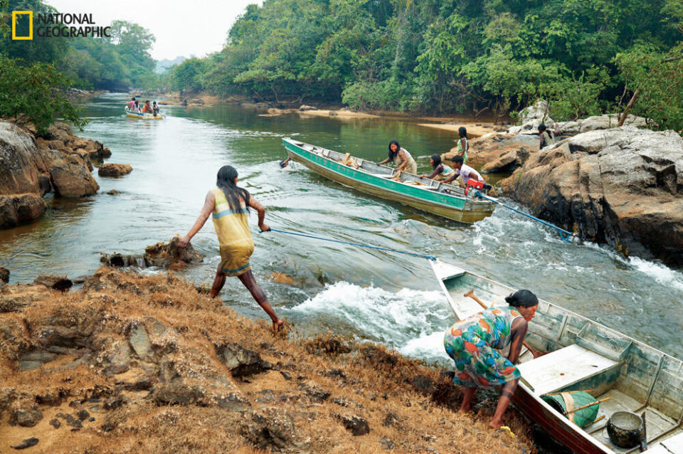 Women from Kendjam haul aluminum skiffs up the gentle, dry-season rapids of the Iriri River on a trip to harvest acai berries and coumarou beans. Men come along to hunt and to protect them from jaguars and other wild animals.