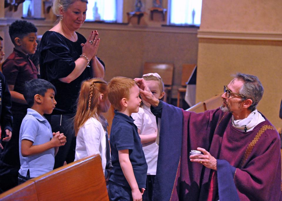 Father Stephen Moran administers ashes to schoolchildren during the Ash Wednesday service at the St. Mary of the Immaculate Conception Church in Wooster on Wednesday.