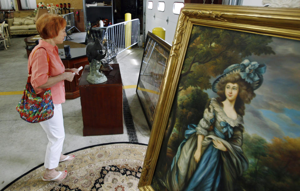 FILE - Reenie Harris of Cedar Knolls, N.J., admires a large framed antique print during a public viewing, of items to be auctioned from the home of former Bernard Madoff finance chief Frank DiPascali, Thursday, June 24, 2010, in Morris Plains, N.J. The U.S. Marshals Service in New Jersey auctioned 51 lots of items that belonged to DiPascali, one of Madoff's closest associates. More than 12 years after Madoff confessed to running the biggest financial fraud in Wall Street history, a team of lawyers is still at work on a sprawling effort to recover money for the thousands of victims of his scam. (AP Photo/Mel Evans, File)