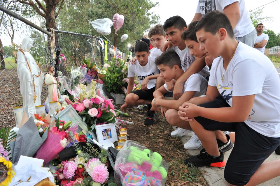 Schoolmates of one of the boys killed gather to pay their respects at a makeshift memorial at the site of an accident which killed four children in Oatlands.