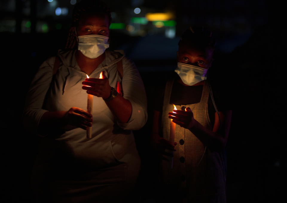 Frontline workers attend a candlelight ceremony on New Year's Eve on the famed Nelson Mandela Bridge in downtown Johannesburg Thursday, Dec. 31, 2020. Many South Africans will swap firecrackers for candles to mark New Year's Eve amid COVID-19 restrictions including a nighttime curfew responding to President Cyril Ramaphosa's call to light a candle to honor those who have died in the COVID-19 pandemic and the health workers who are on the frontline of battling the disease. (AP Photo/Denis Farrell)