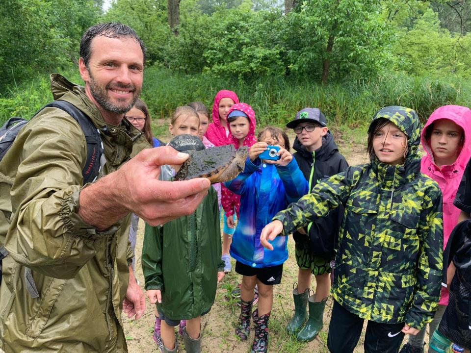 Joe Meyer, executive director of the Catholic Ecology Center, holds a turtle during an educational event. Staff at the center have led everything from ecology programs on birds and insects to foraging workshops, candlelit prayer hikes and feast day celebrations for Catholic saints.