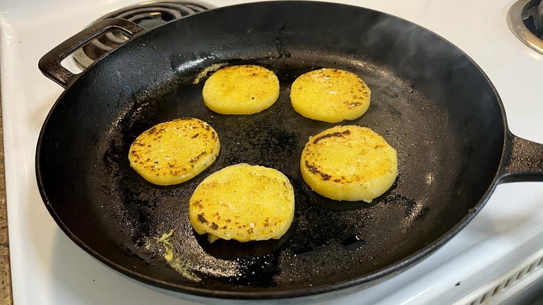 sliced polenta frying in a cast-iron skillet