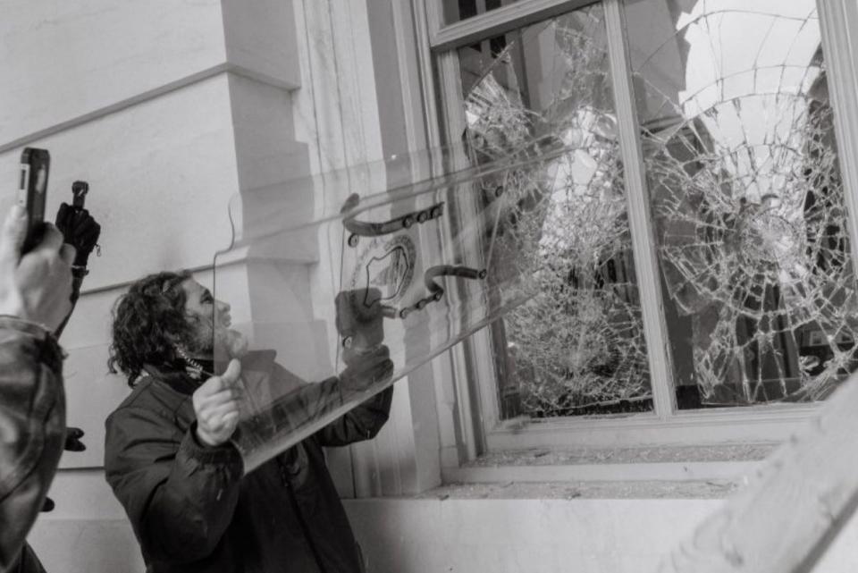 Dominic Pezzola, who the FBI says is a member of the Proud Boys, is shown during the Capitol riot on Jan. 6, wearing an ear piece and using a riot shield belonging to the U.S. Capitol Police to break open a window, according to the FBI.