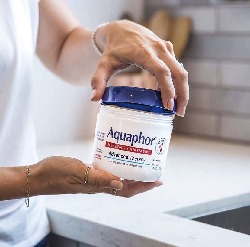 a person holding a jar of aquaphor