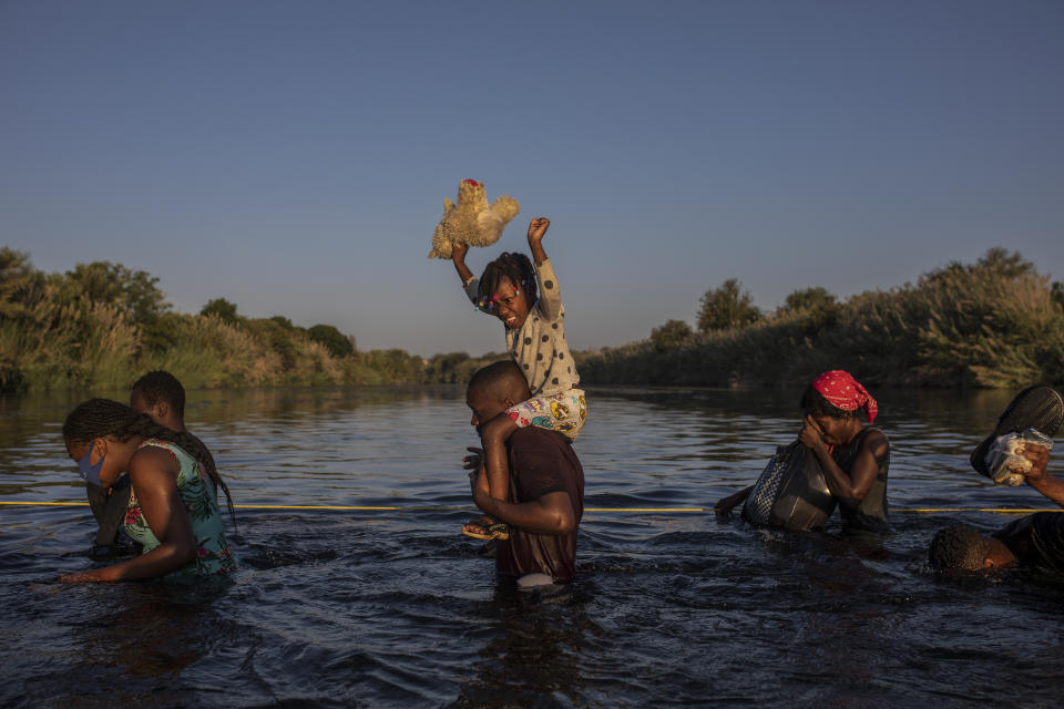 FILE - A girl holds her stuffed animal high above the water as migrants, many from Haiti, wade across the Rio Grande river from Del Rio, Texas, to return to Ciudad Acuña, Mexico, Sept. 20, 2021, to avoid deportation. The U.S. was flying Haitians camped in a Texas border town back to their homeland and blocking others from crossing the border from Mexico. (AP Photo/Felix Marquez, File)