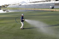 A grounds crew worker waters the 18th green after the PGA tour canceled the rest of The Players Championship golf tournament as a result of the coronavirus pandemic, Friday, March 13, 2020, in Ponte Vedra Beach, Fla. (AP Photo/Lynne Sladky)