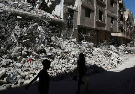 FILE PHOTO: Children walk past rubble of damaged buildings at Ain Tarma, eastern Damascus suburb of Ghouta, Syria July 19, 2017. REUTERS/Bassam Khabieh/File Photo