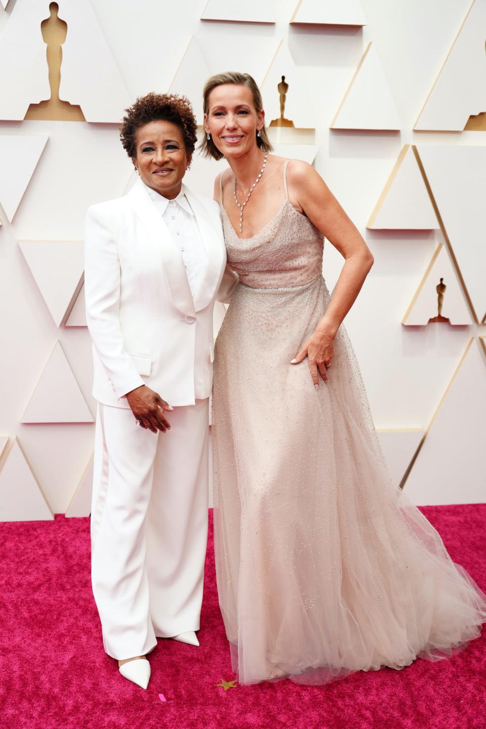 Wanda in a white suit and shirt with pointed heels. Alex in a scoop neckline tulle blush pink dress with crystals and a wide skirt.