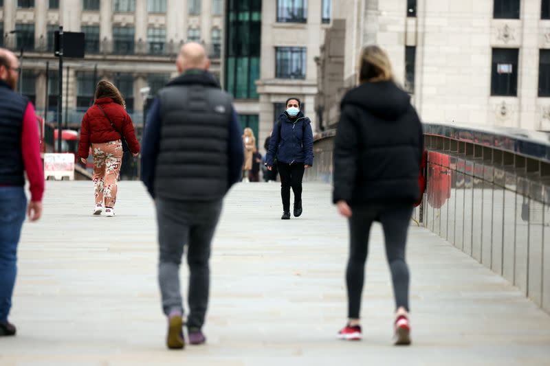 FILE PHOTO: People socially distance as they walk across London Bridge, in London