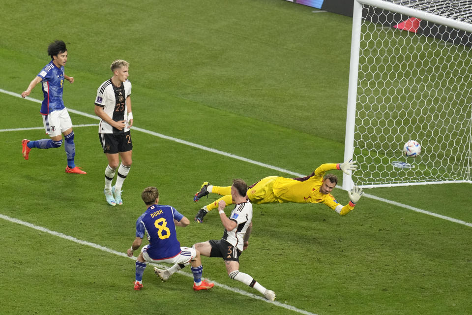 Japan's Ritsu Doan, bottom left, scores his side goal during the World Cup group E soccer match between Germany and Japan, at the Khalifa International Stadium in Doha, Qatar, Wednesday, Nov. 23, 2022. (AP Photo/Ricardo Mazalan)