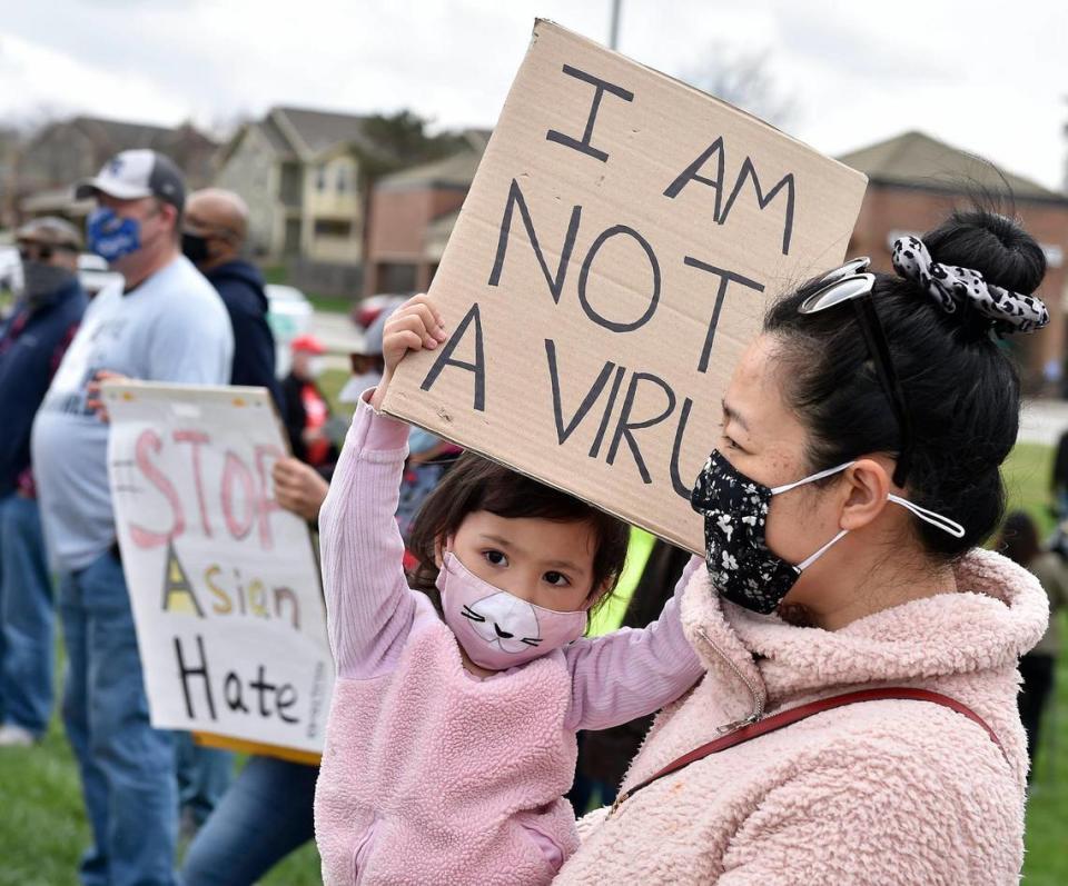 Two-year-old Lucy Smith waves a sign as she and her mom, JiaoJiao Shen participate in a rally. Nearly 150 people attended a rally at Highland Plaza on 119th Street in Overland Park Saturday, March 27, 2021, to bring attention to hate crimes committed against Asian people. A newly formed group, Allies Against Asian Hate, organized the event.