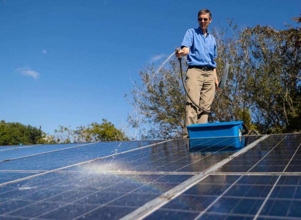 Phil Stoddard, chair of the Green Corridor, cleans the solar panels on his roof on Wednesday, Jan. 31, 2023, in South Miami, Fla.
