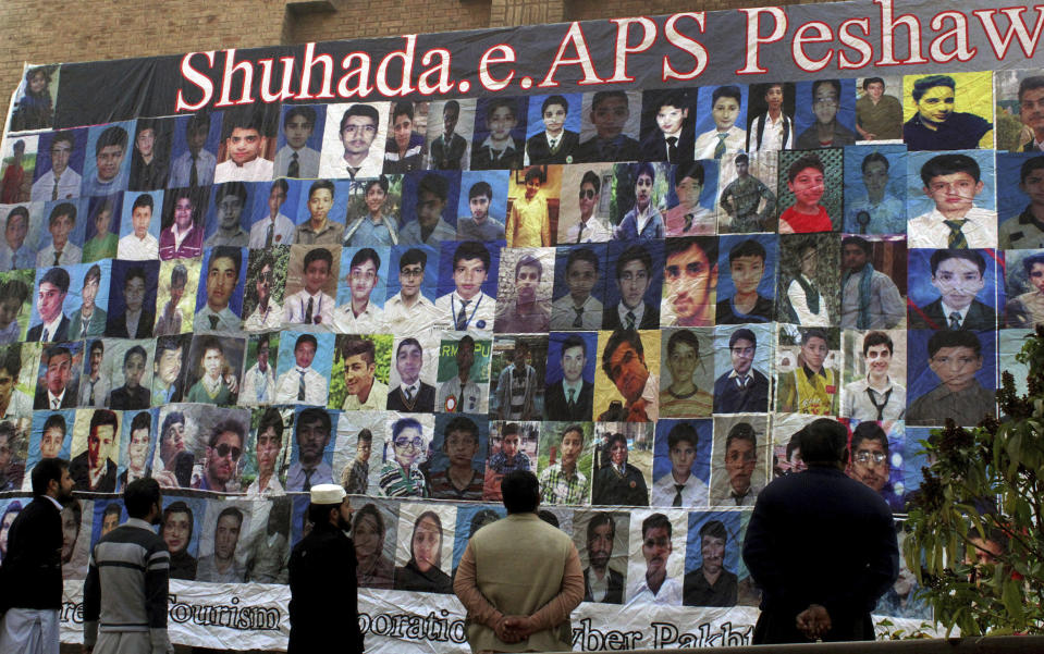 FILE - Pakistanis look at a banner displaying pictures of the victims of an attack by Taliban militants on an army public school in 2014 that killed 150 people, on the second anniversary of the attack, in Peshawar, Pakistan, Dec. 15, 2016. Even as Pakistan leads the effort to get a reluctant world to engage with Afghanistan's new Taliban rulers, the insurgent movement has shown no signs of expelling Pakistani Taliban leaders from its territory, nor of preventing them from carrying out attacks in Pakistan. (AP Photo/Muhammad Sajjad, File)