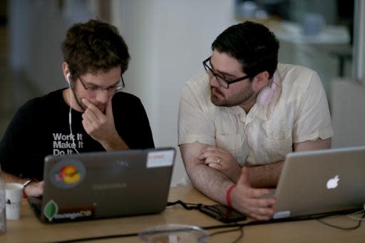 Miguel Chateloin (L) y Lázaro Gamio usan sus computadoras para ingresar códigos que habiliten a gente que vive en Cuba usar el correo electrónico para postar en blogs durante la feria Hackathon para Cuba el 1 de febrero de 2014, en Miami, Florida. (GETTY IMAGES NORTH AMERICA/AFP | Joe Raedle)