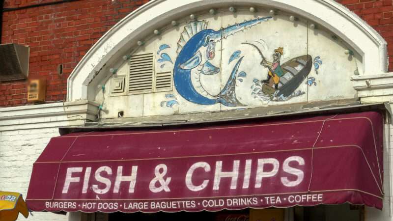 Awning that hangs over the entrance of an English restaurant, reading FISH & CHIPS