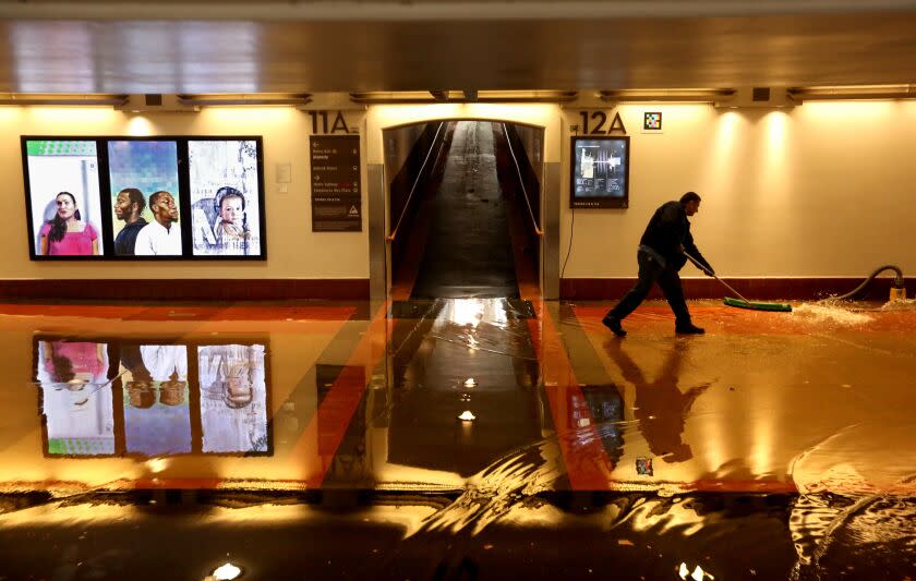LOS ANGELES, CA - JANUARY 10, 2023 - - A Metro worker clears a flooded section of the pedestrian walkway leading to train platforms on the main level of Union Station in downtown Los Angeles on January 10, 2023. Many commuters were shuttled over the flooded section caused by the latest rain storm in Southern California. (Genaro Molina / Los Angeles Times)