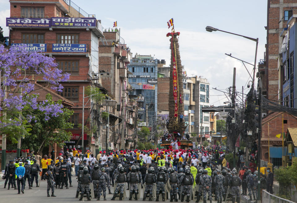 Policemen stand guard as Nepalese devotees pull a chariot during the Rato Machindranath chariot festival in Lalitpur, Nepal, Saturday, May 15, 2021. A truncated version of a Hindu chariot festival took place in Nepal's capital on Saturday amid strict COVID-19 restrictions, following an agreement between organizers and authorities that prevented a repeat of violent confrontations between police and protesters at last year's festival. (AP Photo/Niranjan Shrestha)