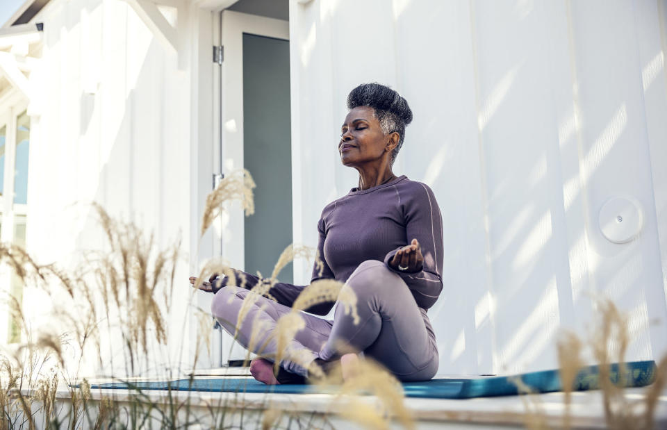 Woman meditating in backyard. (The Good Brigade / Getty Images)