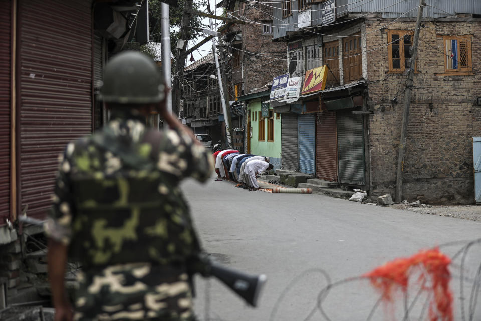 An Indian paramilitary soldier stands guard as Kashmiri Muslims offer Friday prayers on a street outside a local mosque during curfew like restrictions in Srinagar, India, Aug. 16, 2019. The image was part of a series of photographs by Associated Press photographers which won the 2020 Pulitzer Prize for Feature Photography. (AP Photo/Mukhtar Khan)