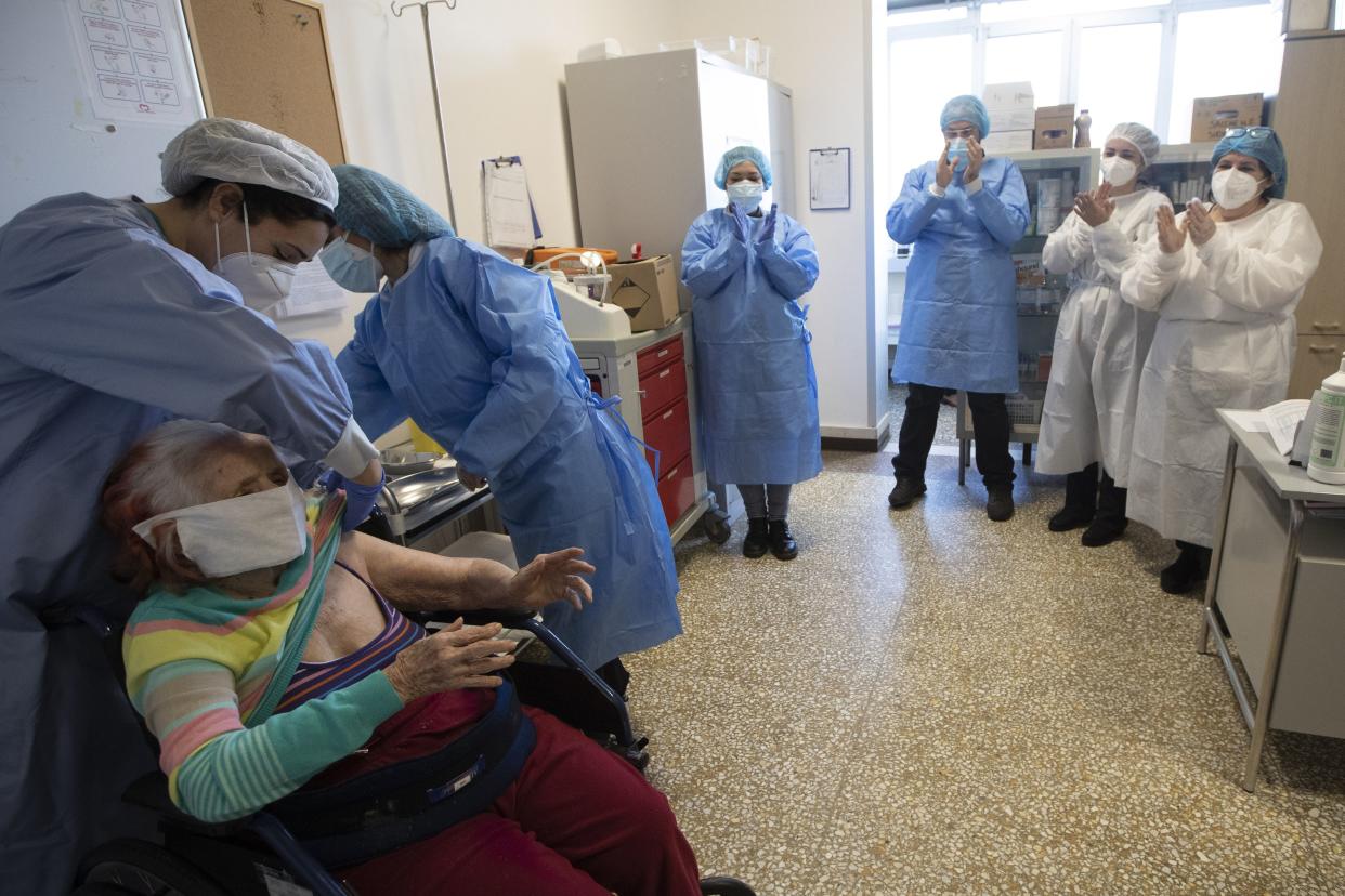 Public Health Service medical personnel applaud after Teresa Poeta, sitting at left, received the COVID-19 vaccine at the Don Orione rest home in Rome, Italy on Saturday, Jan. 2, 2021.