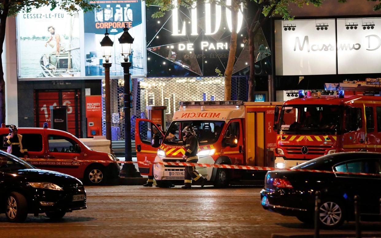 Firefighters and rescuers stand by the site of a shooting on the Champs Elysees in Paris on April 20, 2017 - AFP