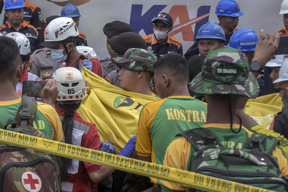 Rescuers remove the body of a train crash victim in Cicalengka, West Java, Indonesia, Friday, Jan. 5, 2024. Two trains collided on Indonesia's main island of Java on Friday, causing several carriages to buckle and overturn, officials said. (AP Photo/Abdan Syakura)