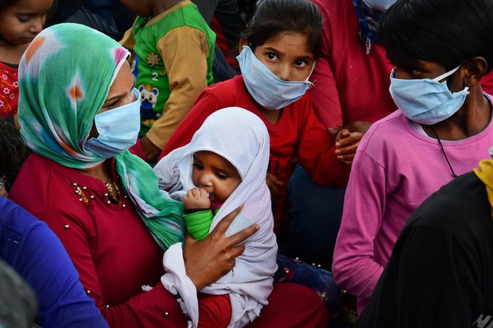 Migrant woman with a baby wearing a face mask as a