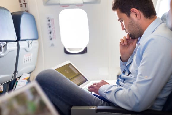 A man working on a laptop on a plane