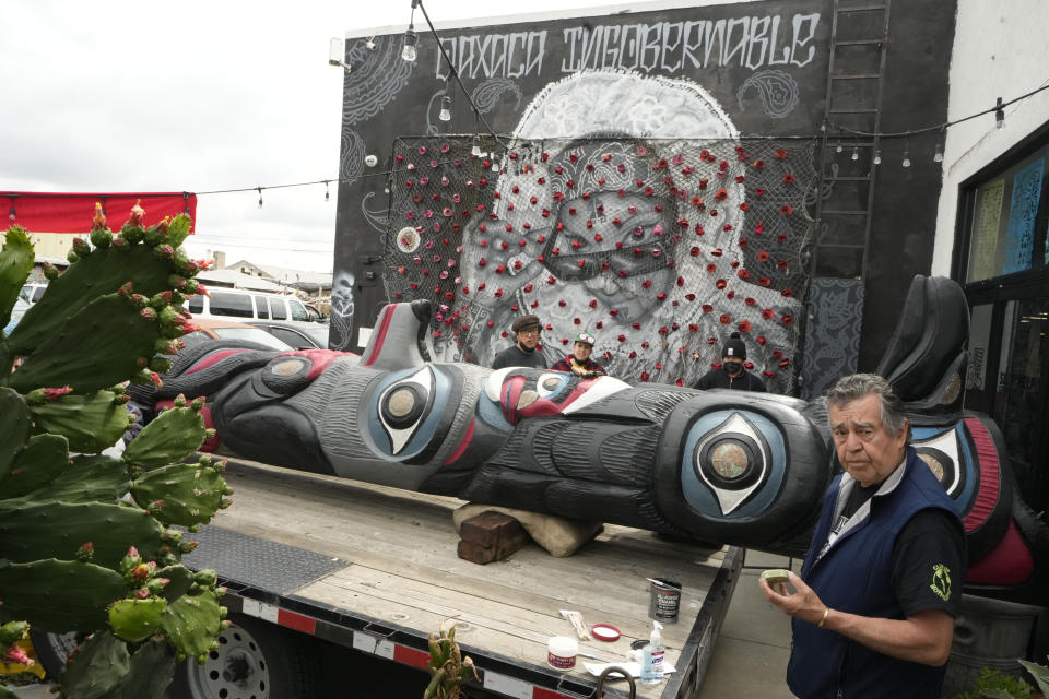 Wood carver Douglas James, 71, a member of the Lummi Nation who traveled from Washington State, retouches the paint of a totem pole touring across the country in an attempt to stop the degradation of Native lands, as he joins members of the Apache Stronghold group gathered at Self Help Graphics & Art in the Los Angeles neighborhood of Boyle Heights in Los Angeles Monday, March 20, 2023. The Apache group battling a foreign mining firm that wants to build one of the largest copper mines in the United States on what tribal members say is sacred land will get a new chance to make its point Tuesday when a full federal appeals court panel takes another look at the case. (AP Photo/Damian Dovarganes)